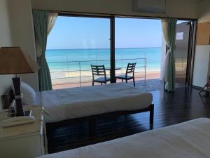 a hotel room with two beds and a view of the ocean at Hotel & Restaurant On the Beach Lue in Motobu