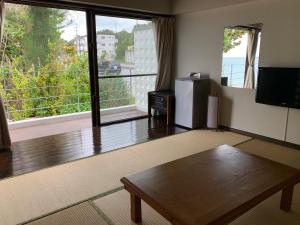 a living room with a table and a large window at Hotel & Restaurant On the Beach Lue in Motobu