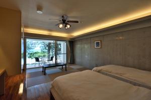 a bedroom with two beds and a ceiling fan at Hotel & Restaurant On the Beach Lue in Motobu
