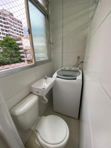 Baño blanco con aseo y lavamanos en Apartamento frente mar Gonzaga Santos, en Santos
