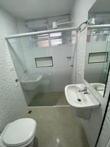 a white bathroom with a toilet and a sink at Apartamento frente mar Gonzaga Santos in Santos