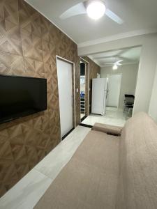 a living room with a couch and a television on a wall at Apartamento frente mar Gonzaga Santos in Santos