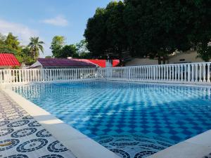 a swimming pool with a white fence and blue tiles at EL DESCANSO DEL HACARITAMA in Melgar