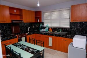 a kitchen with wooden cabinets and a table and a table and a stove at Luxe Furnished Apartments Unit 9 in Meru