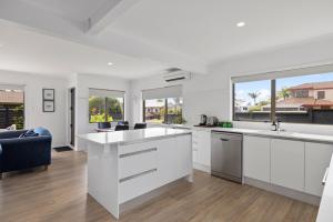a kitchen with white cabinets and a large window at Waitui Wonder - A Comfortable Escape in Mount Maunganui