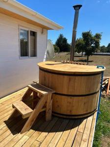 bañera de hidromasaje de madera con banco en la cubierta en Lugar de descanso, con Tinaja al aire libre., en Llanquihue