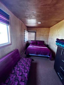 a small room with a purple bed and a window at Lugar de descanso, con Tinaja al aire libre. in Llanquihue