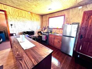 a kitchen with a stainless steel refrigerator and wooden floors at Lugar de descanso, con Tinaja al aire libre. in Llanquihue