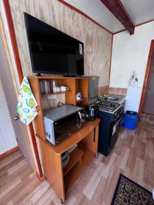 a small kitchen with a microwave and a stove at Acogedor departamento interior, a minutos del Lago in Llanquihue