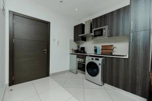 a kitchen with a washing machine and a microwave at Enjoy Luxury Studio w/Pool @Embassy Gardens in Accra