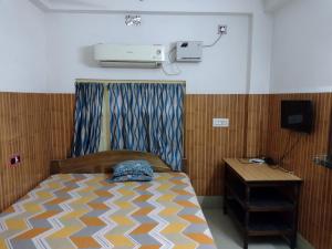 a bedroom with a bed and a nightstand and aperature at Jagannath Guest House in Navadwīp
