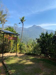 a sign with a palm tree and mountains in the background at Pepper county farm stay in Munnar