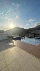 a swimming pool on top of a building with the sun at Apartamento altíssimo padrão - Piscina com vista in Mangaratiba
