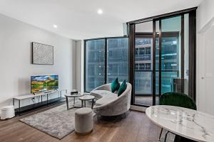 uma sala de estar com um sofá e uma televisão em Lumina Suites em Melbourne