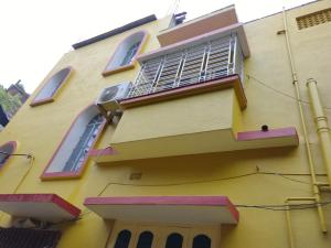 a yellow building with windows and a balcony at Jagannath Guest House in Navadwīp