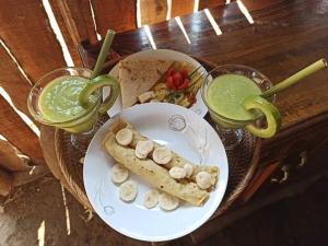une table avec une assiette de nourriture et deux boissons dans l'établissement Girang Rinjani Bungalows, à Tetebatu