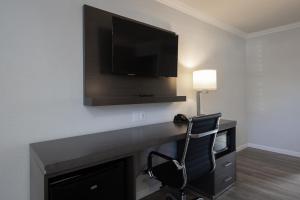 Habitación con escritorio, TV y silla. en Rodeway Inn Milpitas near Great Mall, en Milpitas