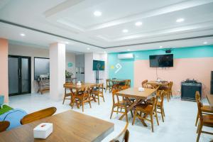 a restaurant with tables and chairs and a flat screen tv at Sans Bougenville Lampung in Lampung