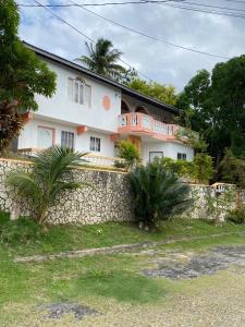 a large white house with a stone wall at Cozy Family Inn in Port Antonio