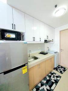 a kitchen with white cabinets and a sink and a microwave at Green 2 Residences Scandi-Industrial Hotel Type Interior in Dasmariñas +24 photos
