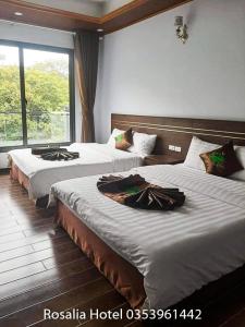 a hotel room with two beds and a window at Ros Hotel Tam Đảo in Tam Ðảo