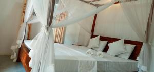 1 dormitorio con cama con dosel y cortinas blancas en Twinkle Tangalle Villa en Tangalle
