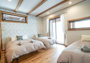a room with three beds and a window at 　白馬　コテージ　チェスナッツ in Hakuba