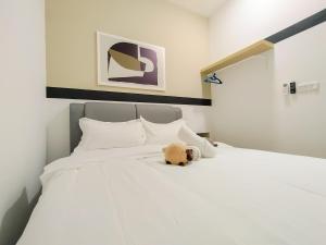 un oso de peluche tirado en una cama blanca en M Vertica By Minsu en Kuala Lumpur