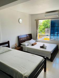 two beds in a room with a window at Apartamentos Sweet Island in San Andrés