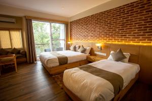 a hotel room with two beds and a brick wall at Himalayan Horizon in Dhulikhel