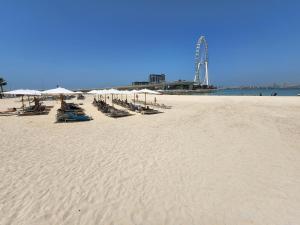 una playa de arena con sillas y sombrillas. en The Star @ Address Beach Residence, en Dubái