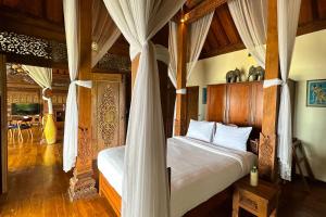 a bedroom with a canopy bed and a dining room at Villa Borobudur Resort in Borobudur