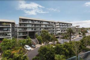 un complejo de apartamentos con coches aparcados en un aparcamiento en Sandy Hill apartment, Sandringham, en Sandringham