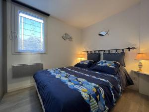 um quarto com uma cama com um edredão azul e uma janela em Appartement Saint-Pierre-d'Oléron, 2 pièces, 4 personnes - FR-1-246A-170 em Saint-Pierre-dʼOléron