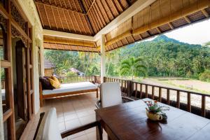 um quarto com uma mesa e cadeiras numa varanda em Villa Manuk em Singaraja