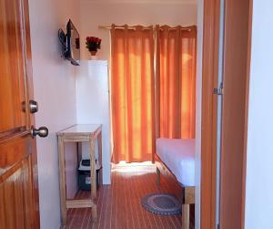 1 dormitorio con cortina naranja y mesa en Foxtail Siargao Island Guesthouse, en General Luna