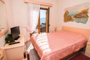 1 dormitorio con cama, TV y balcón en Artemis, en Karpenisi