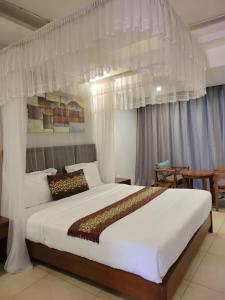 1 dormitorio con 1 cama blanca grande con cortinas en Acholi Inn, en Gulu