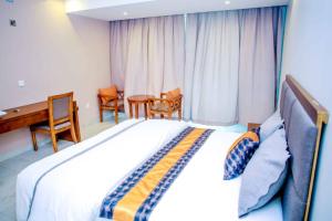1 dormitorio con 1 cama, mesa y sillas en Acholi Inn en Gulu