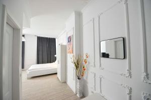 um quarto branco com uma cama e um espelho na parede em Otilia em Bucareste