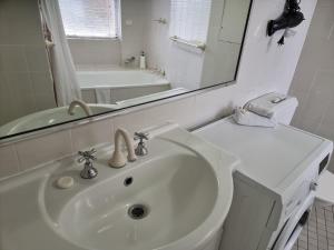 a white bathroom with a sink and a mirror at Accommodation Sydney - Hyde Park Plaza in Sydney