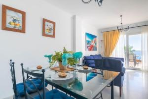a dining room with a glass table and blue chairs at Mi Capricho beach front sea view & pool - Happy Rentals in Mijas Costa