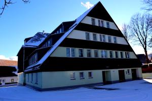 Schwarzes Ross Hotel & Restaurant Oberwiesenthal في كورورت أوبرفايسنتال: مبنى أسود وبيض مع ثلج على الأرض