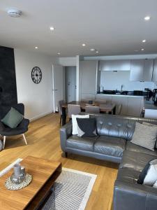 a living room with a leather couch and a table at Lowen in Newquay