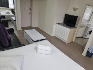 een slaapkamer met een wit bed en een televisie bij Accommodation Sydney - Hyde Park Plaza in Sydney