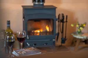 two glasses of wine sitting on a table with a fireplace at Highdown Farm Holiday Cottages in Cullompton +18 photos