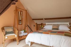 a bedroom with a large bed and a chair at Highdown Farm Holiday Cottages in Cullompton