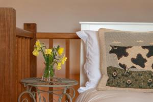 un jarrón de flores en una mesa junto a una cama en Highdown Farm Holiday Cottages, en Cullompton