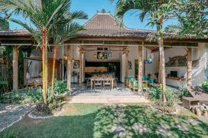 a house with a patio with a table and palm trees at Contemporary Balinese 4BR Private Villa in Umalas in Kerobokan