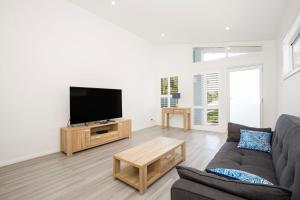 a living room with a couch and a flat screen tv at Sanctuary Blue Pet Friendly 5 Mins to Hyams Beach in Sanctuary Point